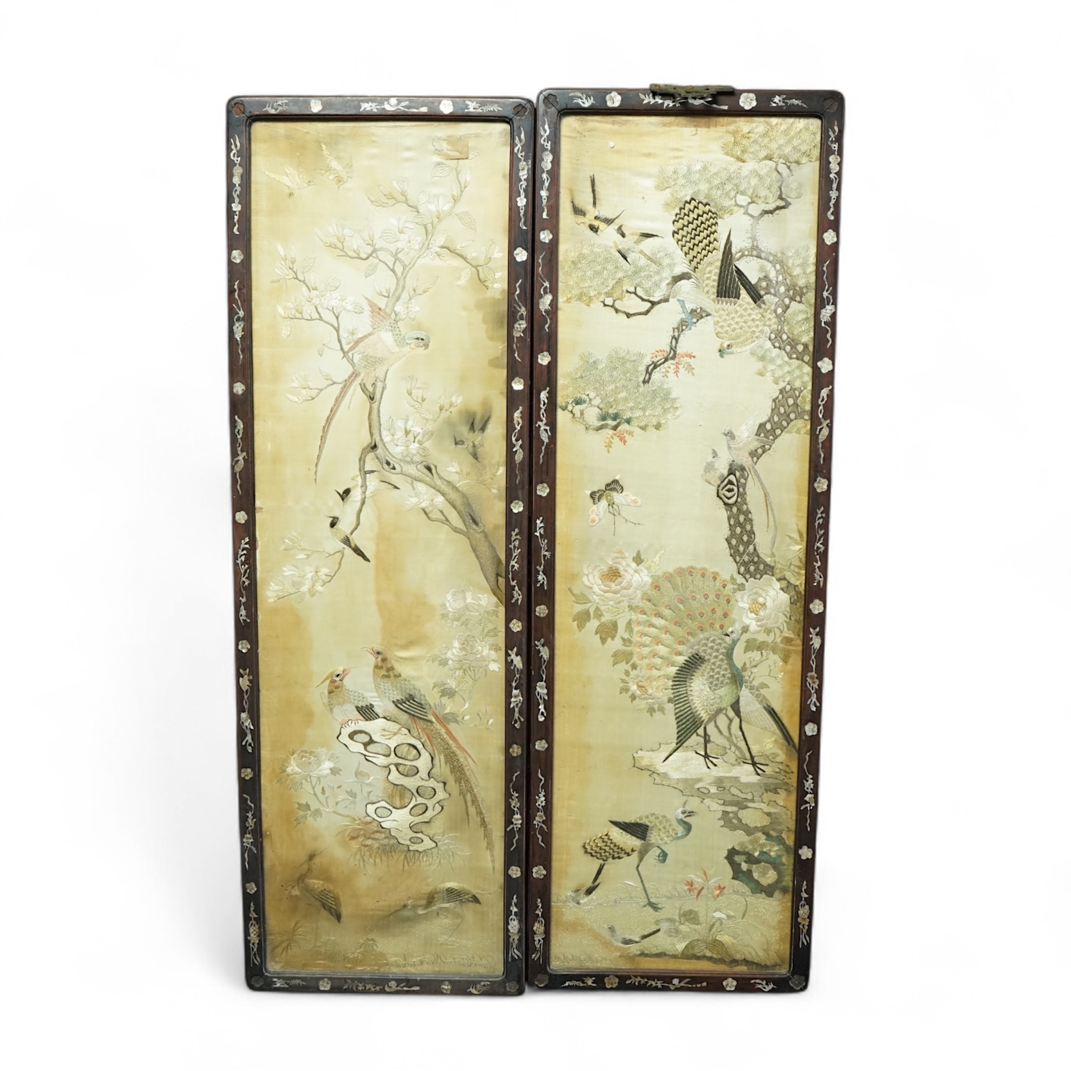 A pair of Chinese embroidered ‘Hundred Bird’ silkwork pictures, c. 1900, in Hongmu and mother-of-pearl inlaid frames, total size 99cm x 32cm. Condition - dark staining and tears to the silk, losses to the mother of pearl
